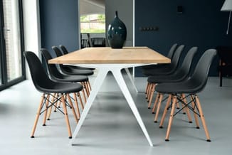Moderne vergadertafel met wit onderstel en houten blad, omgeven door zwarte stoelen met houten poten in een kantoorruimte met