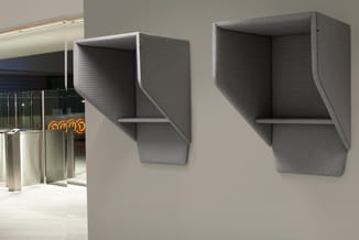 Twee grijze wandgemonteerde akoestische boxen met ingebouwde legplanken in moderne kantooromgeving.