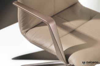 Beige stoel met gebogen armleuning en gestoffeerde zitting, detail van ergonomisch ontworpen kantoorstoel.