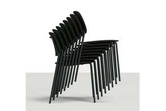 Stapel zwarte kunststof stoelen met metalen poten op grijze vloer, gestapeld in perspectief.