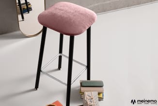 Roze barkruk met zwarte poten en zilveren voetsteun in moderne kantoorruimte, naast materiaalstalen.