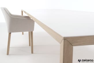 Houten vergadertafel met beige gestoffeerde stoel met houten poten in minimalistisch interieur.