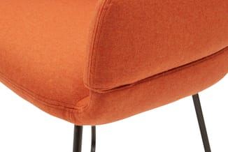 Oranje stoel met fluweelachtige bekleding en zwarte metalen poten, detail van zitting en rugleuning.