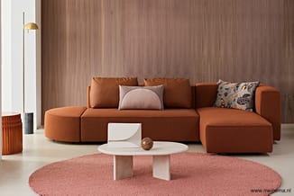 Moderne zithoek met terracottakleurige modulaire bank, witte ronde salontafel, roze rond vloerkleed, houten wandbekleding en