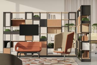 Modern kantoorinterieur met modulaire zwart-metalen kast, oranje sofa, beige fauteuil, planten, boeken en tv-scherm tegen wit