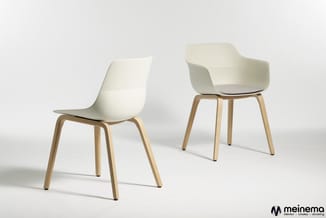 Twee witte designstoelen met houten poten op neutrale achtergrond. Linksstoel zonder armleuningen, rechterstoel met armleunin