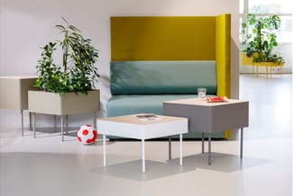 Moderne kantoorzithoek met geel-groen gestructureerde rugsteun, witte en grijze salontafels, beige plantenbak met groen en ro