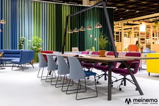 Moderne kantoorruimte met lange tafel, grijze stoelen, hangende verlichting, groene golflijn achterwand, kleurrijke zithoeken