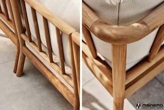 Houten loungestoel met beige textielkussen, detail armsteun en spijlen, op betonnen vloer.