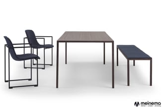 Minimalistisch kantoorinterieur met twee zwarte stoelen met armleuningen, grijze houten tafel en donker houten bankje tegen w