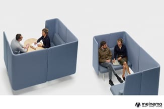 Twee blauwe akoestische belcellen met afgeschermde zitruimtes. Links twee personen bij ronde tafel, rechts twee personen op z