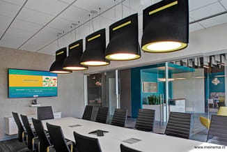 Moderne vergaderruimte met witte tafel, zwarte ergonomische stoelen met gele accenten, hangende zwart-gele designlamp, glazen