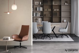 Modern kantoorinterieur met cognackleurige loungefauteuil, witte bureaukstoelen, zwart tafelonderstel, grijze werkplek en bru