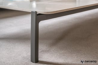 Grijze metalen pootsteun onder tafelblad met beige beklede zijpanelen op grijs tapijt in kantoor.