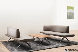 Moderne zithoek met twee grijze loungebanken, houten salontafel, zwarte metalen poten, grijze vloerkleed, houten vloer, groen