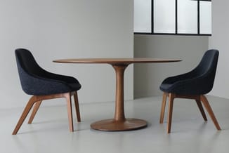 Ronde houten tafel met centraal voetsstuk, omgeven door twee zwarte stoelen met houtenen poten in moderne designstijl.