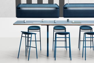 Moderne kantoorruimte met blauwe barstoel met gevoerde zitting, grijs werkblad, zwarte barkrukken en donkerblauwe wandpanelen