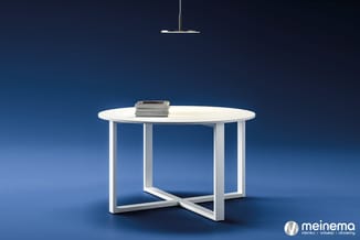 Witte ronde tafel met kruisvormig onderstel op blauwe achtergrond, gestapelde boeken op het blad, hanglamp erboven. Meinema-l