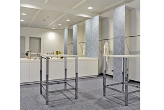 Moderne badkamer met witte kasten, grijze tegelmotieven op wanden, spiegels, grijs terrazzo vloer en metallic frames.