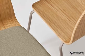 Houten stoelen met beige zitgedeelte en grijze metalen poten, detail zijaanzicht met meinema-logo.