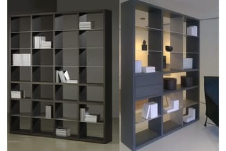 Twee zwarte open kasten met vakken; links gevuld met witte boeken, rechts gedeeltelijk als ruimteverdeler met decorobjecten e