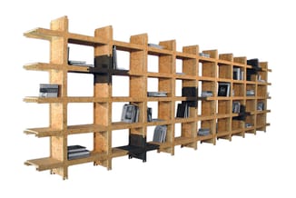 Modulair kastensysteem van kurk met meerdere open vakken, zwarte inzetstukken en boeken en apparatuur op verschillende niveau