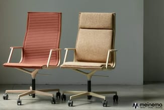 Twee draaistolen met wielen op grijs oppervlak: rode stoel met horizontale ribbelpatroon en beige stoel met gestoffeerde bekl