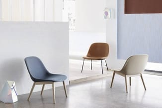 Drie moderne loungestoelen in blauwe, bruine en crèmekleur met houten poten in minimalistisch interieur.