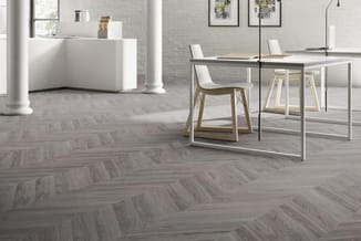 Modern kantoorruimte met grijze visgraatparketvloer, witte receptiebalie, houten stoelen, glazen vergadertafel en minimalisti