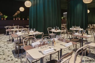 Moderne restaurantruimte met houten tafels, beige stoelen met groene zittingen, gedekte tafels, hangende rotan lampen, groenb