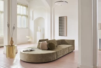 Moderne loungeruimte met beige modulaire bank, ronde vorm, gouden bijzettafel, decoratieve kussens, houten vloer en minimalis