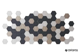 Hexagonale akoestische wandpanelen in grijs, zwart en beige, gerangschikt in abstract patroon op witte achtergrond.
