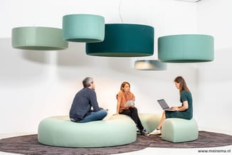 Drie personen op ronde mint-groene loungemeubels in werkruimte met hangende cilindervormige akoestische panelen in groen en t
