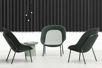 Drie groene stoelen met zwarte metalen poten rond een lichtgroen bijzettafeltje in minimalistisch interieur met geribde grijz
