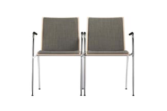 Twee grijze wachtstoelen met houten rug, chromen armleuningen en metalen poten, in tandem opgesteld tegen witte achtergrond.