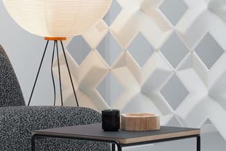 Kantoorruimte met grijze designstoel, driepoot vloerlamp met rieten kap, houten tafel met zwarte en houten accessoires, witte