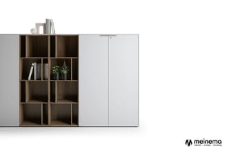 Modulair kastensysteem met open houten vakken, witte schuifdeuren en zwevende top met boeken en decoratie.