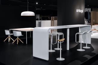 Moderne kantoorinrichting met wit curved eiland, tafel met witte stoelen met houten zitting, baarstoelen, hangend plafondlamp