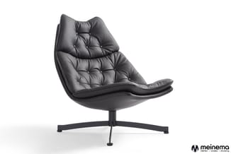 Zwarte lederen fauteuil met gestoffeerde zitting, capitonnered design, op vierpoots zwart metalen voet tegen witte achtergron