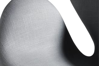 Grijze gestoffeerde zitmeubel met textielweefsel, detail van zitting en rugleuning met schaduwwerking.