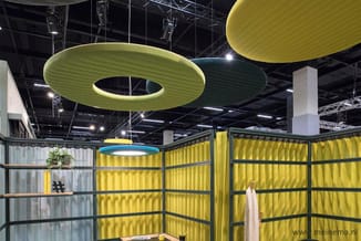 Kantoorruimte met gele geluidswerende wanden, ronde groene akoestische plafondpanelen en moderne verlichting.