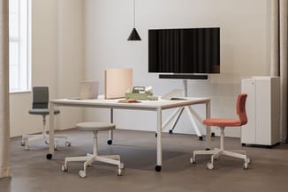 Modern kantoorinterieur met lichte houten tafel, grijze en oranje bureaukstoelen op wielen, witte kasten, zwarte hanglamp en