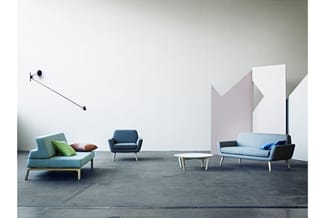 Showroom met grijze betonvloer: turquoise loungebank met kussens, donkerblauwe fauteuil, lichtblauwe sofa met kussens, witte