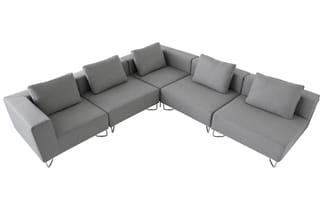 Grijze modulaire hoekbank met meerdere zitplekken, gecombineerde elementen, kussens en metalen poten tegen witte achtergrond.