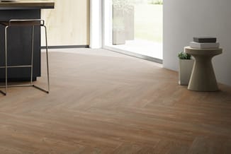 Moderne kantoorruimte met visgraat houten vloer, zwarte garderobekast links, ronde beige bijzettafel met plantenbak rechts en