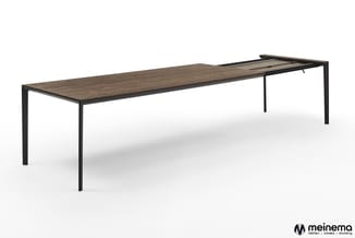 Lange vergadertafel met donkerbruin houten blad en zwart metalen frame, gezien vanuit schuine hoek.