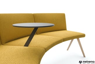 Gele zitbank met houten poten en zwart tafeltje met rond tafelblad, meinema-logo.