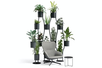 Grijze fauteuil omringd door zwarte plantenbakken op standaards met diverse groene planten, aangevuld met zwart bijzettafeltj