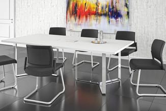 Moderne vergadertafel met wit blad en zilverkleurig onderstel, omringd door zwarte netwerk stoelen met verchroomde poten in k
