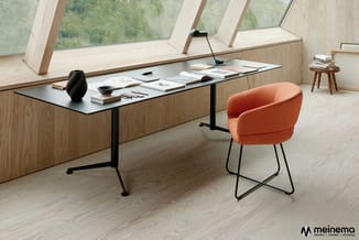 Moderne kantoorruimte met zwarte werkplank op houten onderkast, oranje gestoffeerde stoel met metalen poten, zwarte bureaulam